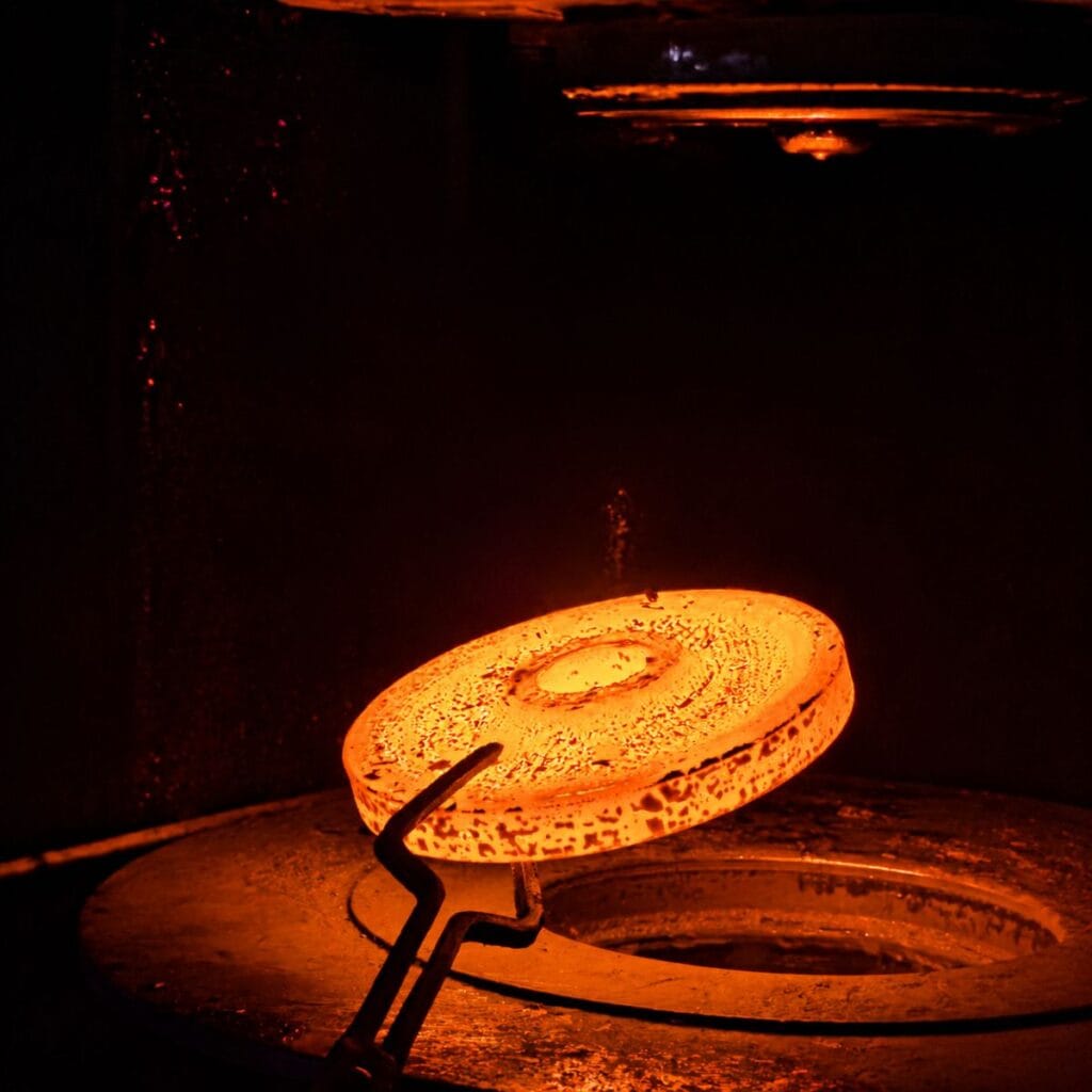 Heated steel workpiece in a closed die forging process for manufacturing high-strength precision forged OEM components