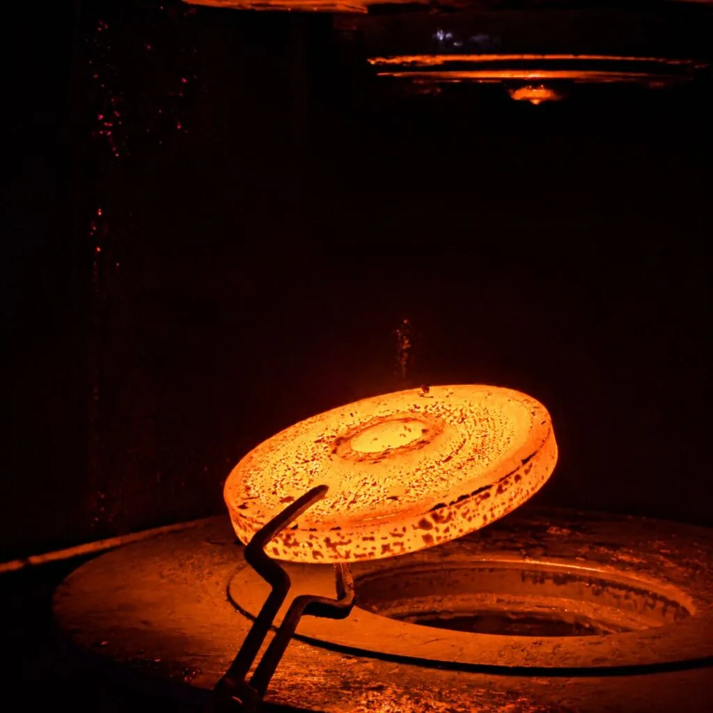 Heated steel workpiece in a closed die forging process for manufacturing high-strength precision forged OEM components