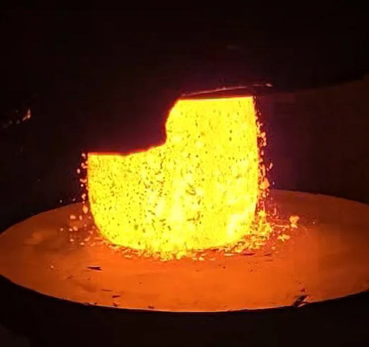 Procédé de forgeage à chaud montrant un bloc d'acier chauffé à haute température lors du forgeage industriel