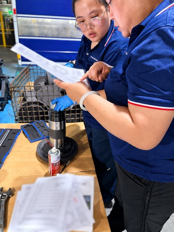 Operators reviewing an engineering drawing during in-process quality inspection of a forged component