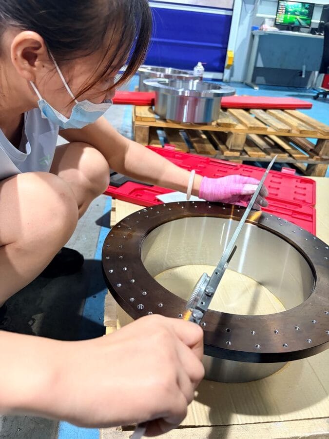 Technician inspecting the machined bore of a robot joint rotor core